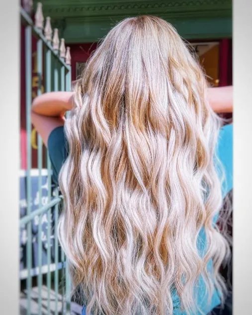 Long blonde wavy tape-in hair extensions with warm golden tones at Fluff Hair Extensions Studio