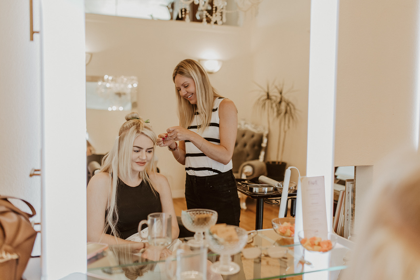 Stylist and client smiling during an extension appointment at Fluff